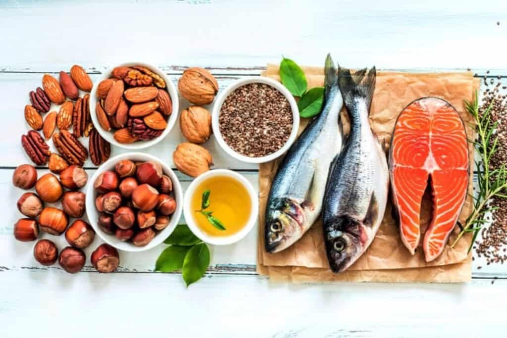 Fresh fish, nuts, seeds, and healthy oils on a rustic white wooden table, promoting holistic living and nutritious eating.