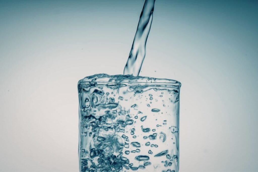 A clear glass of fresh from a countertop Reverse Osmosis Water Filter with bubbles rising, symbolizing clean, toxin-free hydration essential for natural wel.